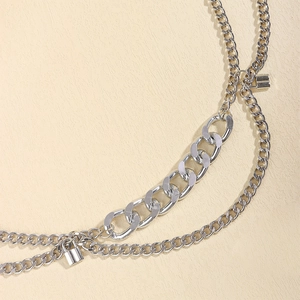 Detail of silver layered chain belt with curb links and delicate padlock charms