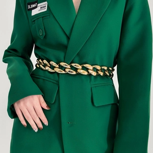 Close-up of chunky gold chain belt with oval links on a dark green blazer jacket