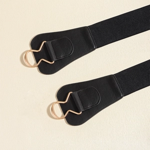 Detailed macro view of black elastic corset belt with a wavy golden metal buckle