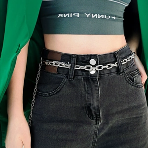 Close-up of a silver chunky chain waist belt with tassel detail on black jeans