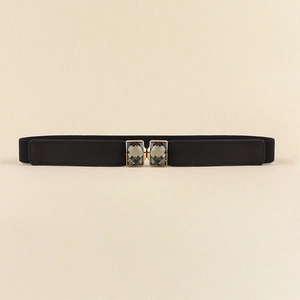 Détail de ceinture élastique noire avec deux strass vert émeraude en monture dorée