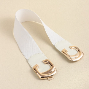 Detail of white elastic waist belt featuring a polished gold horseshoe buckle design