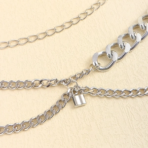 Detail of silver multi-layer chain belt featuring punk style link patterns and small padlock