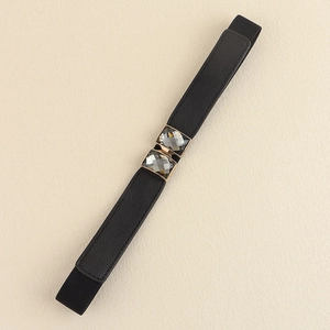 Détail d'une ceinture élastique noire ornée de cristaux gris et d'un bord doré chic