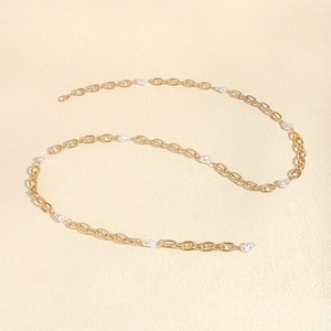 Detail of gold metal link chain with white baroque pearls for dresses and beach style