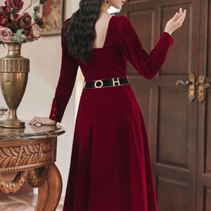 Detailed back view of a dark red velvet dress with pearl collar and black belt with gold buckle