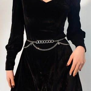 Detail of silver multilayer chain belt with thick rings and fine drapes on black velvet dress