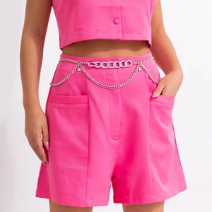 Detail view of silver metal waist chain with layered links and mini lock charms on a pink suit