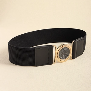 Détail d'une ceinture élastique noire avec une grande boucle ronde dorée et un insert texturé