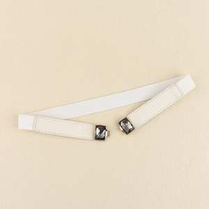 Détail d'une ceinture élastique blanche avec boucle en strass gris et finition en similicuir