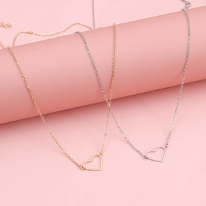 Collane con ciondolo a cuore in oro e argento su sfondo rosa in stile minimalista