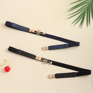 Detail view of thin elastic waist belts in black and navy with golden knot buckles