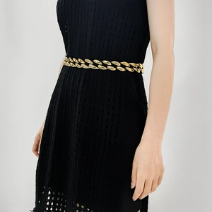 Close-up of a chunky gold chain belt styled on a black dress for a punk aesthetic look