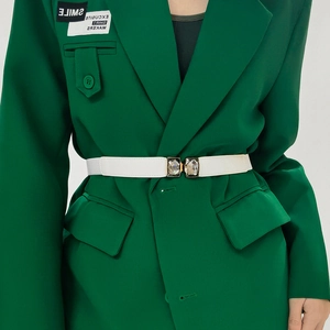 Gros plan d'une ceinture élastique blanche avec boucle en cristal sur un blazer vert