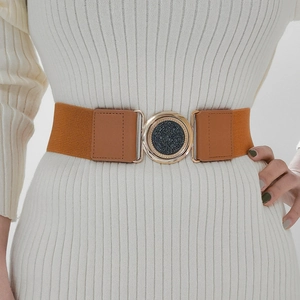 Détail de la ceinture élastique marron caramel avec boucle dorée sur robe blanche