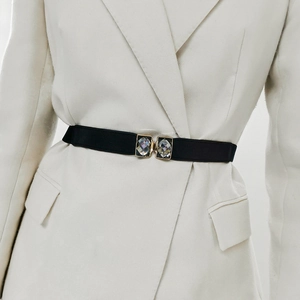 Détail d'une ceinture élastique noire avec boucle en strass doré sur un blazer