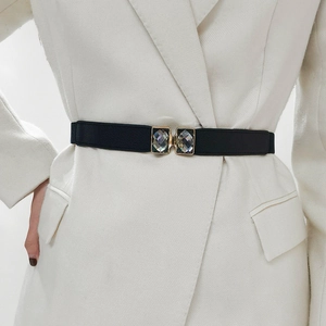 Détail d'une ceinture élastique noire avec boucle dorée et grands cristaux carrés clairs