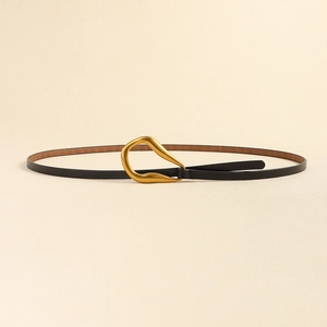 Détail d'une fine ceinture en cuir noir avec une boucle dorée de forme artistique fluide