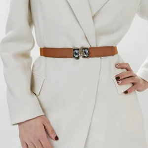 Détail d'une ceinture fine en similicuir marron avec boucle carrée dorée sertie de strass