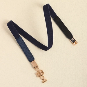 Detailed macro view of navy elastic belt with golden Chinese knot buckle and leather accents