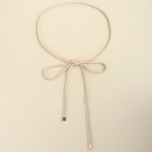 Detail view of a beige woven knotted dress belt featuring elegant gold square metal ends