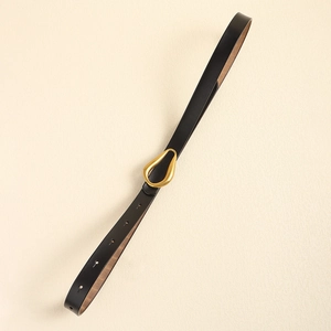 Détail d'une ceinture en cuir noir avec une boucle métallique dorée en forme de goutte