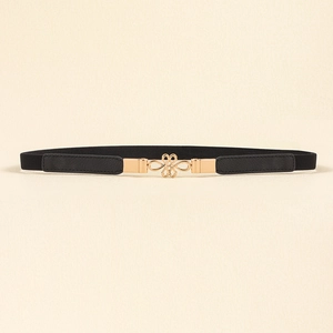 Detail showing elegant gold infinity knot buckle on a slim black elastic waist belt