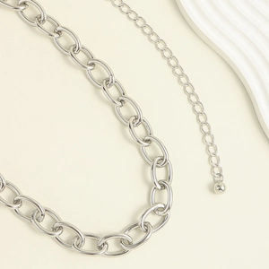 Close-up of a silver chunky metal chain belt with a smooth ball pendant and link details