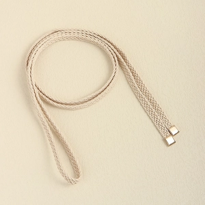 Detail of hand-woven beige rope belt with square gold metal end caps for dresses
