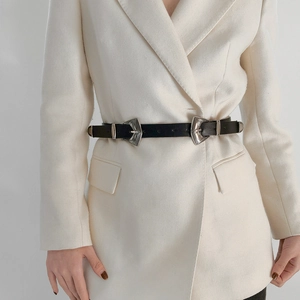 Détail de boucles argentées ciselées vintage sur une ceinture en cuir noir avec blazer
