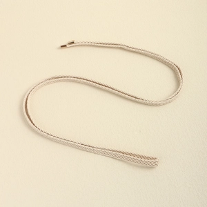 Detail of beige woven waist rope with elegant gold metal aglets and refined texture