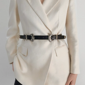 Détail de la ceinture en cuir vintage à double boucle gravée sur un blazer blanc cassé