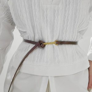 Cintura sottile in pelle marrone da donna con fibbia a treccia dorata su abito bianco