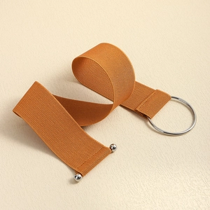 Detailed close-up of brown elastic waist belt with large silver round buckle and metal studs