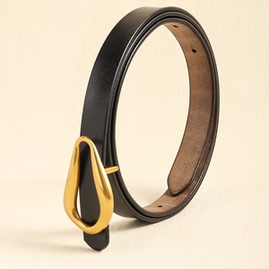 Détail d'une fine ceinture en cuir noir avec une élégante boucle dorée en goutte