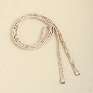 Detail of hand-woven beige rope belt with elegant gold square metal end tips