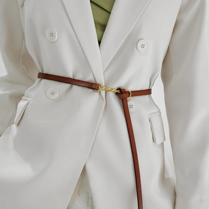 Dettaglio della sottile cintura in pelle marrone con fibbia dorata su un blazer