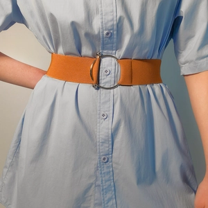 Close-up of caramel brown elastic waist belt with silver double ring buckle on blue shirt