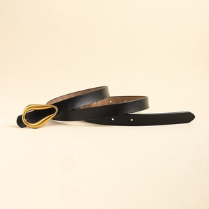 Détail d'une ceinture fine en cuir pour femme avec boucle dorée en forme de goutte