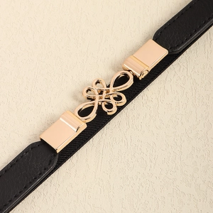 Close-up of golden alloy knot buckle with black elastic thin waist belt for women