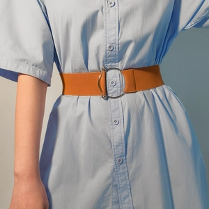 Close-up of a wide camel elastic waist belt with a polished silver round buckle on a dress