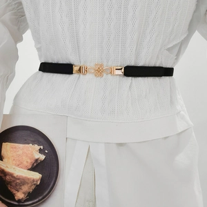 Detail of thin elastic belt with golden Chinese knot metal buckle on white clothes