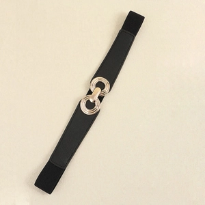 Detail of elegant black elastic waist belt featuring a gold interlocking ring metal buckle