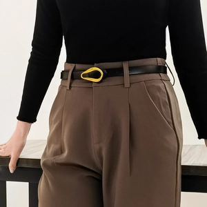 Vue détaillée d'une ceinture fine en cuir noir avec une boucle dorée mate en forme de goutte