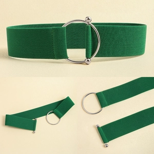 Detail view of a wide green elastic waist belt with a large silver round metal buckle