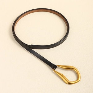 Détail d'une ceinture en cuir noir minimaliste avec boucle dorée en forme de goutte