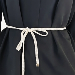 Detail of hand-woven cream waist rope with gold metal tips on a black blazer
