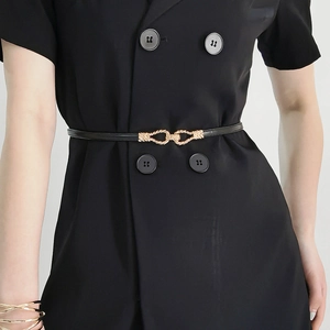 Detail of slim black leather belt with golden twisted rope buckle on a blazer dress