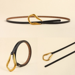 Détail d'une fine ceinture en cuir noir avec boucle dorée profilée irrégulière pour femme