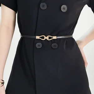Close-up of slim black leather belt with golden twisted buckle on a blazer dress